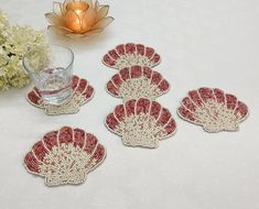 four red and white coasters sitting on top of a table next to a vase