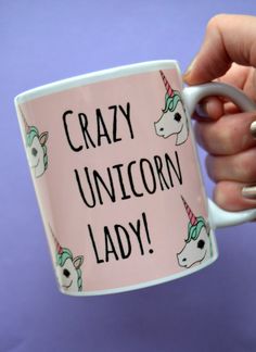 a person holding a coffee mug with the words crazy unicorn lady on it and a pink background