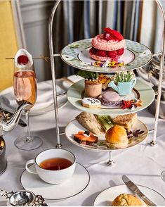 three tiered trays filled with pastries and tea on a white table cloth