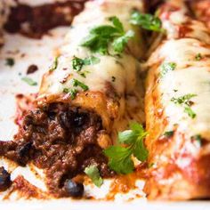 a white dish filled with meat and cheese enchiladas