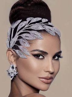 a woman wearing a silver headpiece with leaves on it's forehead and earrings