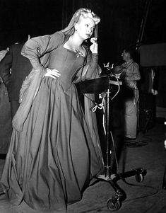 a black and white photo of a woman in a dress talking on a cell phone