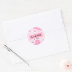 an envelope with a thank you sticker on it next to a pen and flower