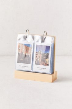 two small photos are placed on a wooden stand with metal rings attached to the sides