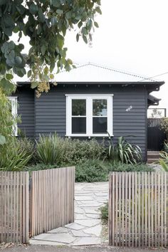 a grey house with white windows and wooden fenced in area next to the yard