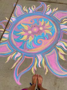 a person standing in front of a sidewalk with chalk pastel art painted on it