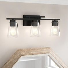 three light bathroom fixture with clear glass shades on the wall and mirror in front of it