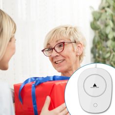 an older woman holding a red gift box and talking to a young lady with glasses