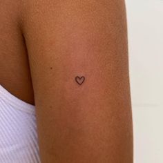 a small heart tattoo on the back of a woman's left upper arm,