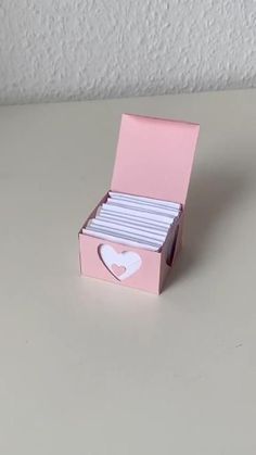 a pink box with white heart cut out of the front and inside, sitting on a table