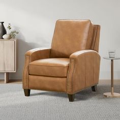 a tan leather recliner chair sitting on top of a carpeted floor next to a side table