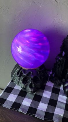 a purple ball sitting on top of a black and white checkered table cloth next to a stuffed animal