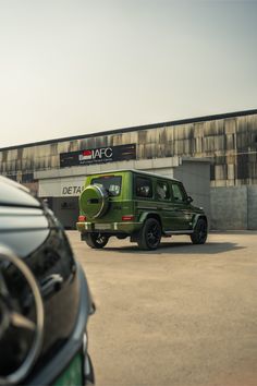 a green jeep parked in front of a building