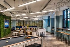 a pool table in a room with lots of tables and stools