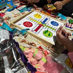 a group of people sitting around a table playing a game with candy and candies