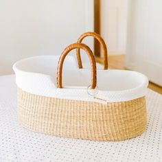 a wicker bassinet with two handles on top of a white tablecloth