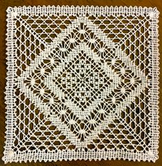 a white crocheted doily on a brown surface