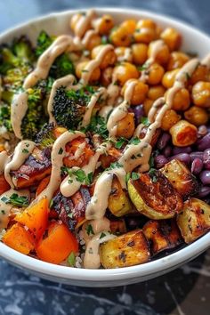 a white bowl filled with different types of vegetables and dressing on top of each other