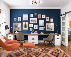 a home office with blue walls and pictures on the wall, including an orange chair