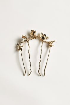 three gold flower hair pins on a white background