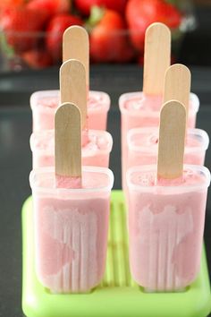 four popsicles in cups with toothpicks sticking out of the top one is pink