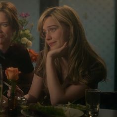 two women sitting at a table with food and drinks