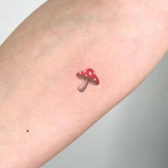 a small mushroom tattoo on the left arm and wrist, with a tiny red mushroom on it's side