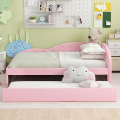 a child's bedroom with green walls and pink bed frame, white pillows and stuffed animals on the floor