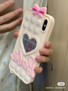 a person holding a cell phone case that has a heart and name on the back