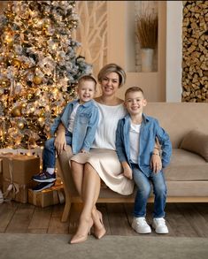 a woman and two children sitting in front of a christmas tree