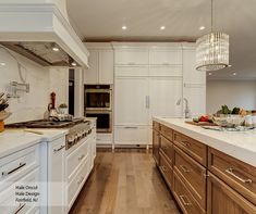 a large kitchen with white cabinets and wood flooring, along with an island in the middle