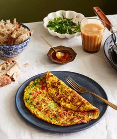 an omelet on a blue plate with a fork and knife next to it