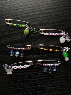 four hair clips with beads and charms on them sitting on a wooden surface, one has a heart