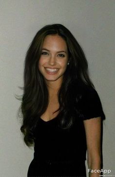 a woman with long dark hair smiling at the camera