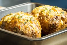 two cooked stuffed potatoes in a metal pan