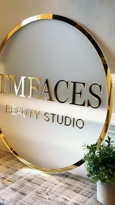 a white and gold sign that says imfaces beauty studio next to a potted plant