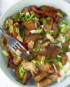 a white bowl filled with meat and vegetables on top of rice next to a fork