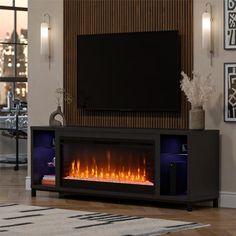 a living room with a large television and fire in the fireplace, it's dark