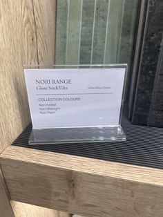 a close up of a business card on a wooden shelf in front of a window