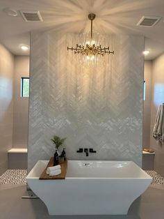 a bath room with a large white tub and a chandelier hanging from the ceiling