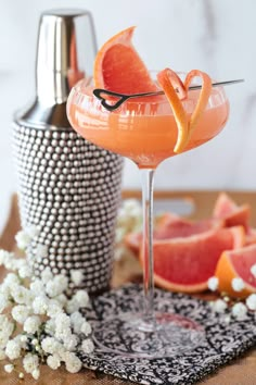 a grapefruit cocktail in a martini glass with an orange slice on the rim