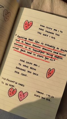 an open notebook with writing on it and hearts drawn on the pages in red ink