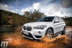 a white bmw suv is driving through the mud