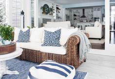 a living room with wicker furniture and blue rugs on the floor in front of it