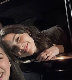 two women are smiling in the back of a car