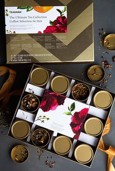 an assortment of teas in tins on top of a table next to ribbons