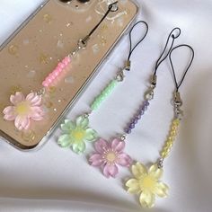 four different colored flowers are attached to the back of an iphone case with ear buds