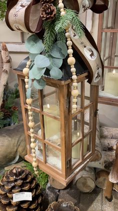 a lantern with candles and pine cones on it