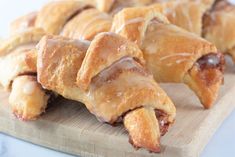 a wooden cutting board topped with pastries covered in glaze