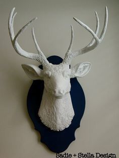 a white deer head mounted to the side of a wall with antlers on it